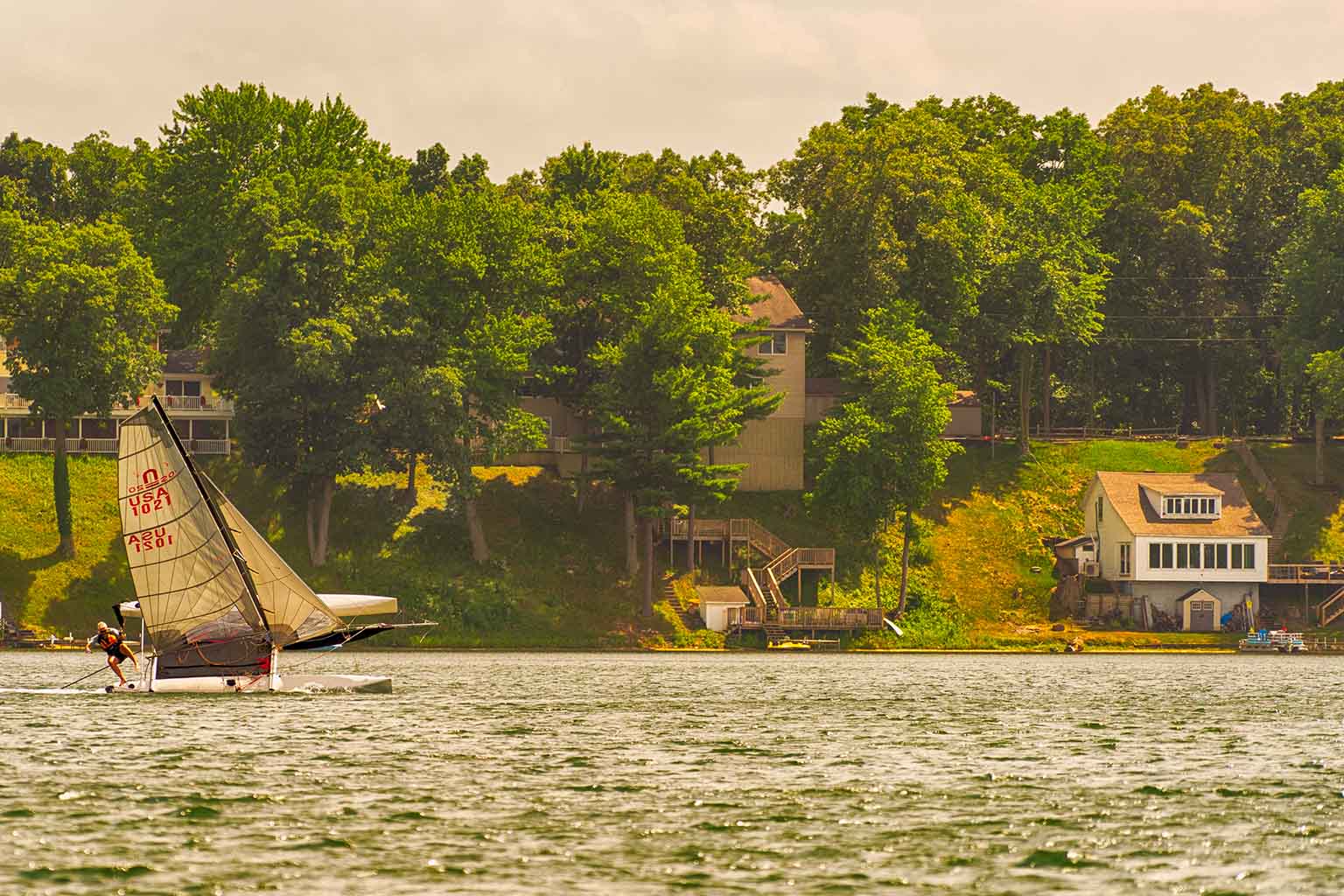 A sailboat glides by houses 